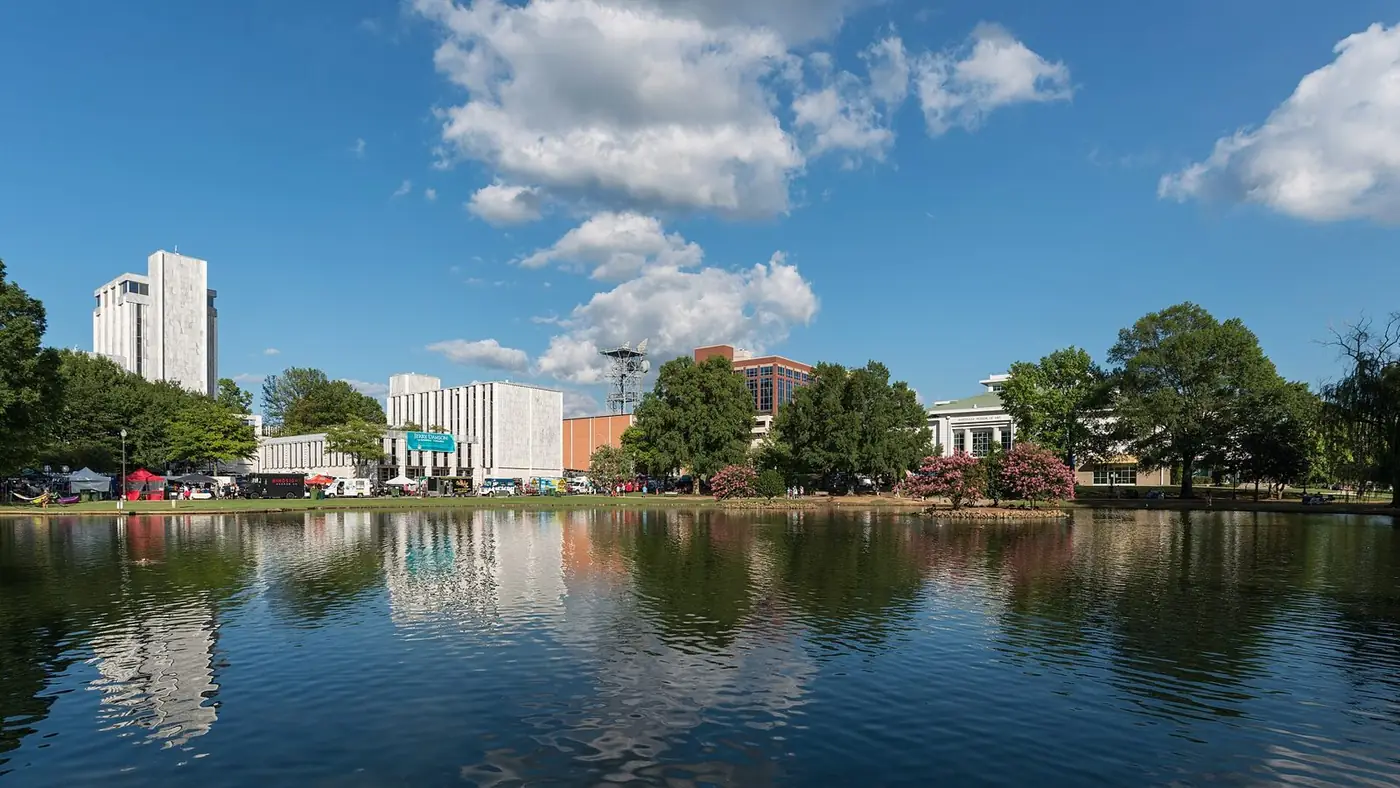 Pond in a downtown park with office buildings and trees reflected in it