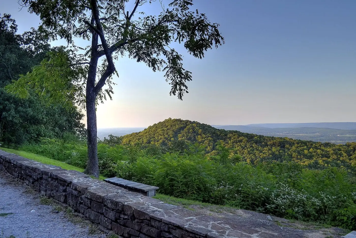 Wooded ridges and a valley seen from a stone-walled overlook
